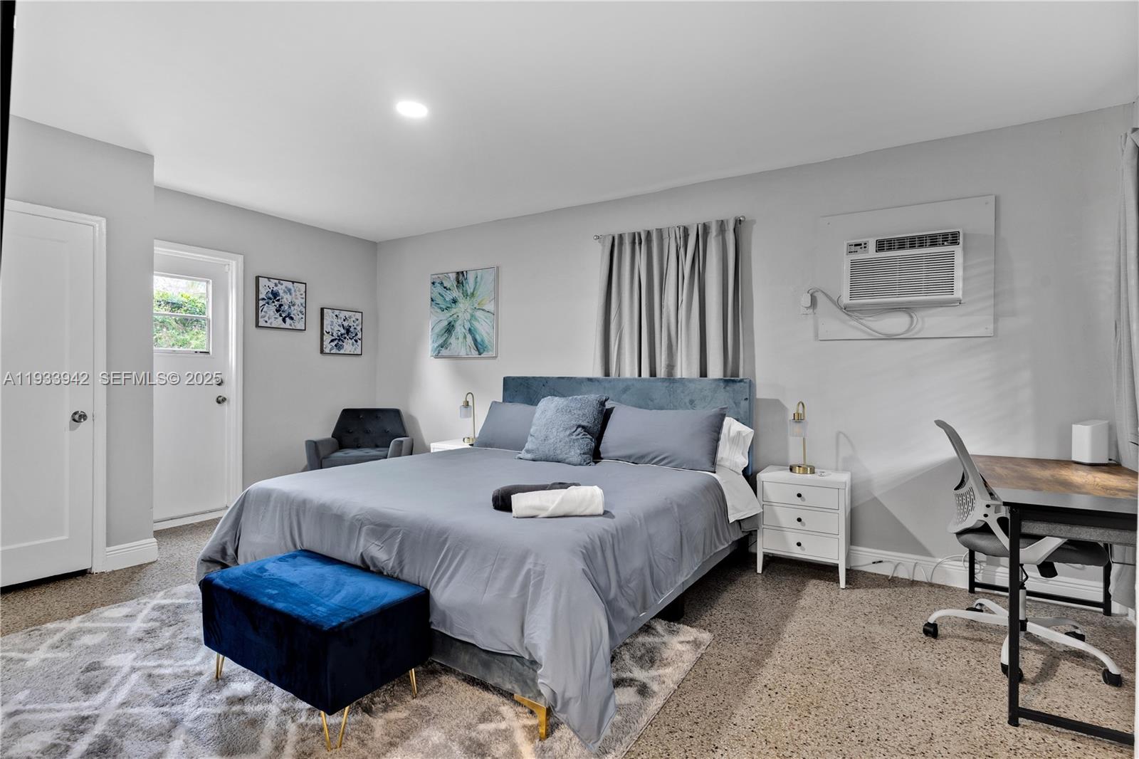 A bedroom features a blue upholstered bed, a desk, and a wall-mounted air conditioner — 427 NE 107th St # 2, Miami FL 33161, MIAMI, FL