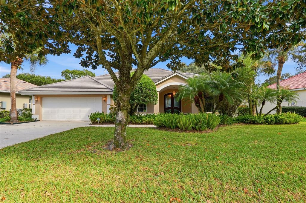 A single-story house with a two-car garage, a large tree, and landscaping in the front — 108 LAKE REGION BOULEVARD N, WINTER HAVEN, FL