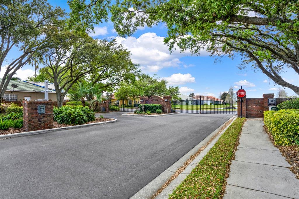 A paved walkway leads to the arched entryway of a tan house with double doors — 108 LAKE REGION BOULEVARD N, WINTER HAVEN, FL