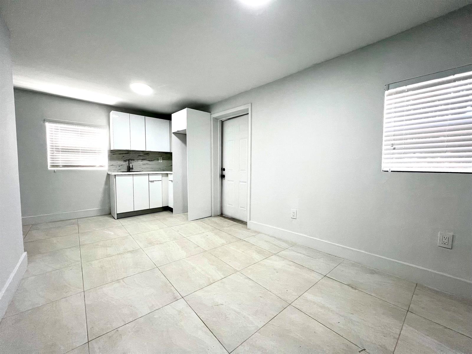 A small kitchen area with white cabinets, light tile flooring, and two windows — 10730 SW 149th Terrace, Miami FL 33176, MIAMI, FL