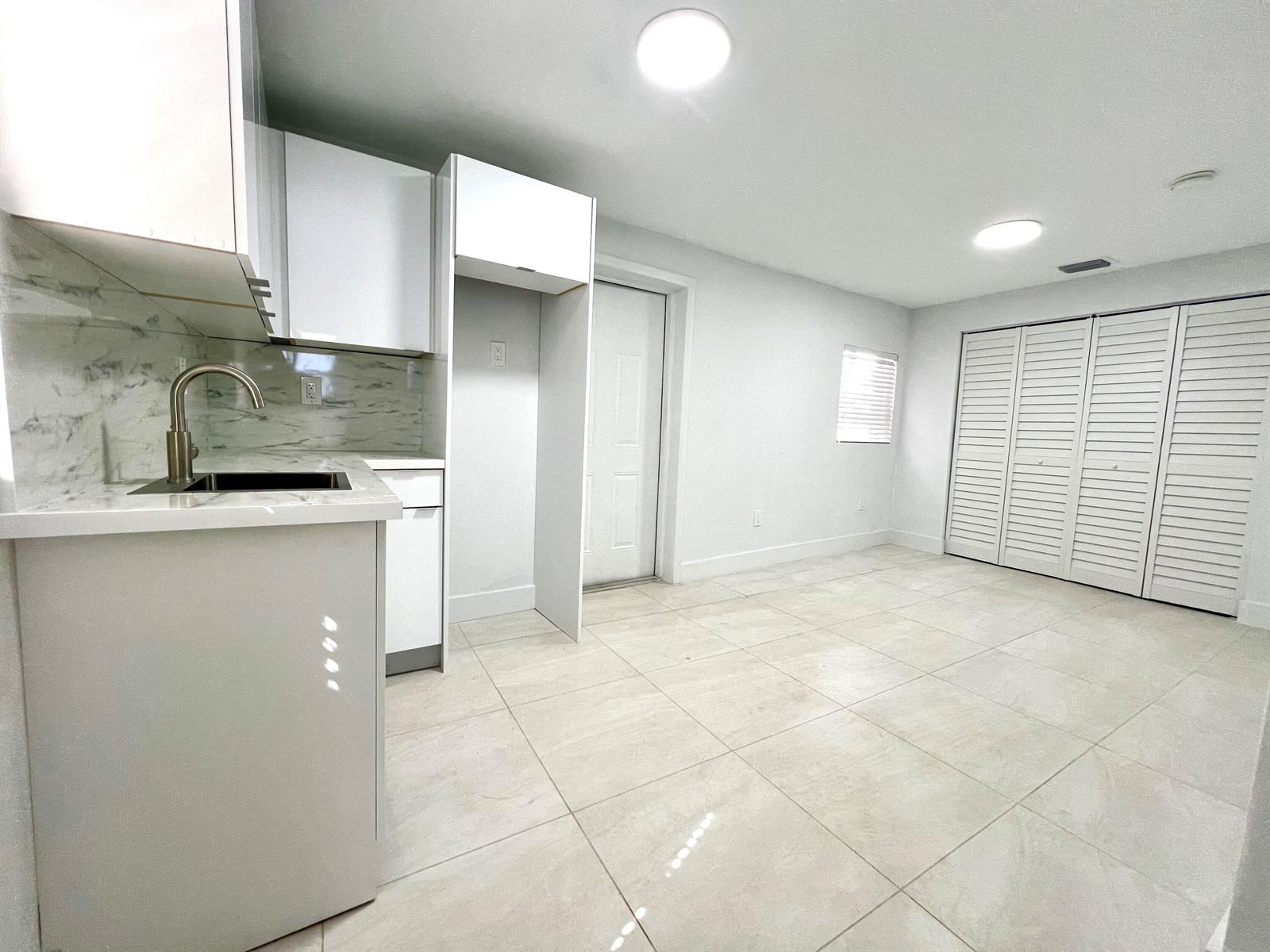 A kitchen area features white cabinets, marble-patterned backsplash, and light-colored tile flooring — 10730 SW 149th Terrace, Miami FL 33176, MIAMI, FL