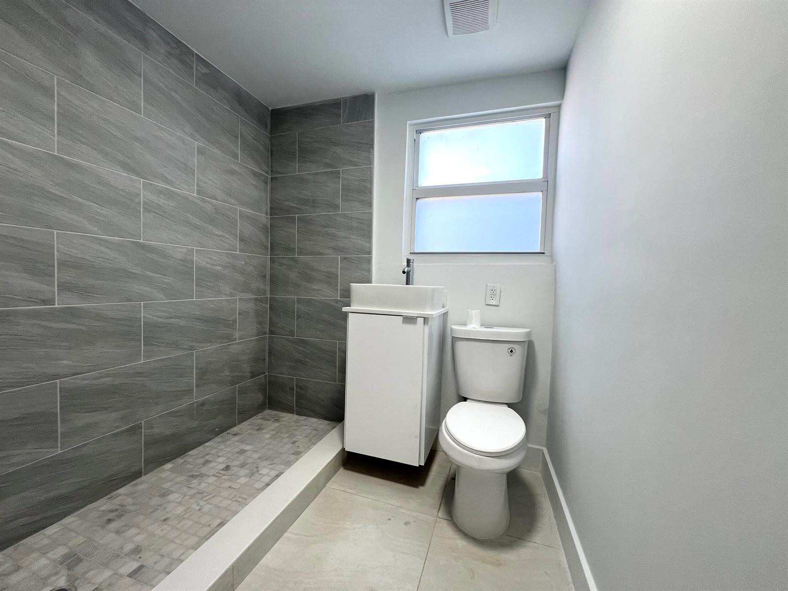 A bathroom features a walk-in shower with gray tile, a white vanity, and a toilet — 10730 SW 149th Terrace, Miami FL 33176, MIAMI, FL