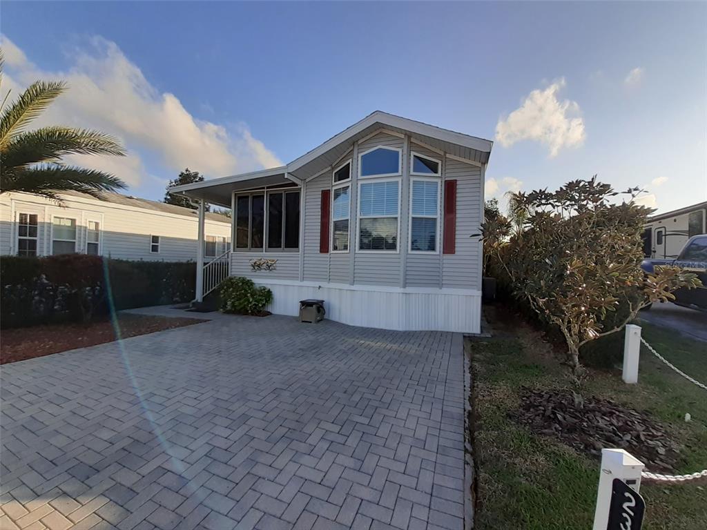 A light gray manufactured home with a paved driveway and a bay window front — 2330 LIMEWOOD AVENUE UNIT 051, CLERMONT, FL
