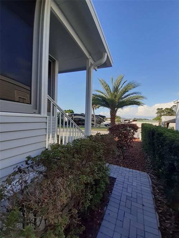 A view of a house exterior featuring a covered porch, walkway, and palm tree — 2330 LIMEWOOD AVENUE UNIT 051, CLERMONT, FL