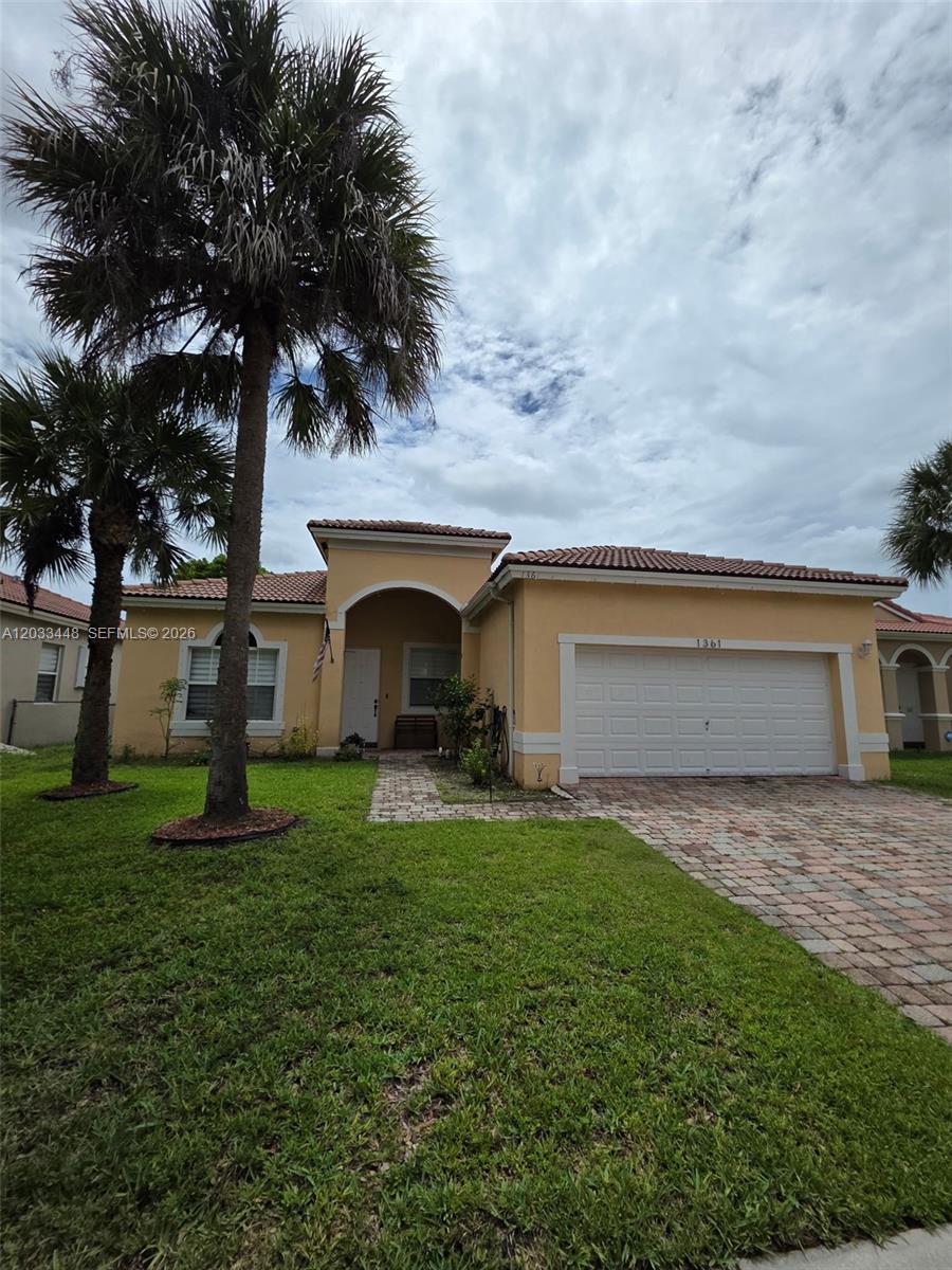 A single-story house with a tan stucco exterior, tile roof, and a paved driveway — 1361 SE 16th Ave, Homestead FL 33035, HOMESTEAD, FL