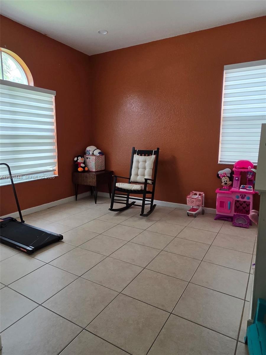 A room with terracotta-colored walls, tile flooring, a rocking chair, and a toy kitchen — 1361 SE 16th Ave, Homestead FL 33035, HOMESTEAD, FL