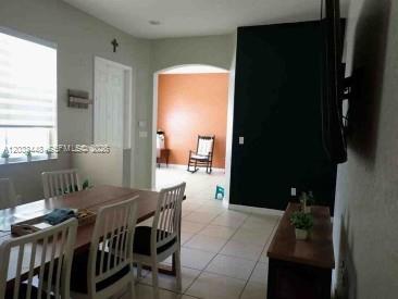 A dining area with a wooden table and chairs leads to an arched doorway — 1361 SE 16th Ave, Homestead FL 33035, HOMESTEAD, FL