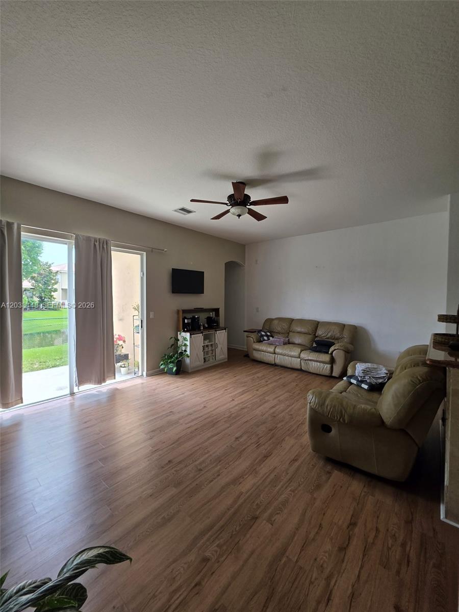A living room features wood-look flooring, two tan leather sofas, and sliding glass patio doors — 1361 SE 16th Ave, Homestead FL 33035, HOMESTEAD, FL