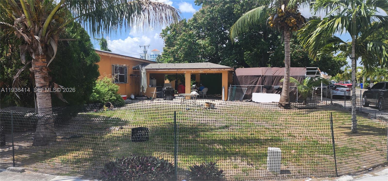A fenced yard features a palm tree, a covered patio, and a brown canopy structure — 5428 NW 13th Ave, Miami FL 33142, MIAMI, FL