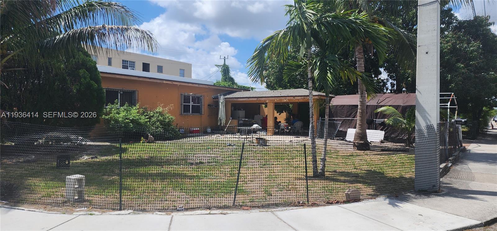 A single-story orange house with a covered patio sits behind a chain-link fence — 5428 NW 13th Ave, Miami FL 33142, MIAMI, FL