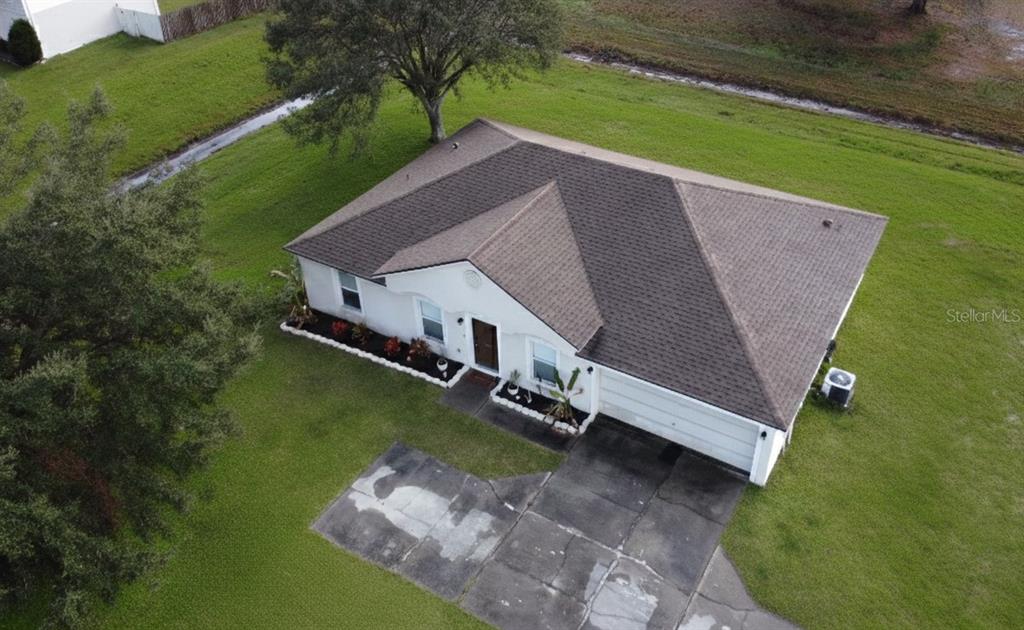 An aerial view of a single-story house with a brown roof and a concrete driveway — 1346 DUNBARTON COURT, KISSIMMEE, FL