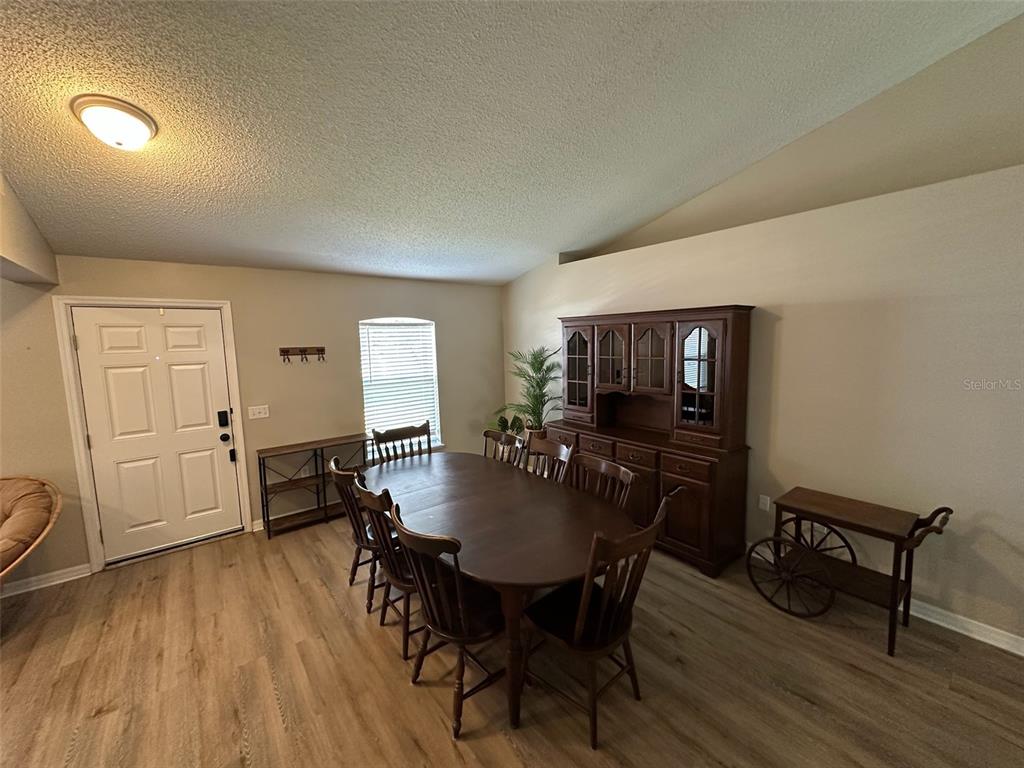 A dining room features a wooden table, chairs, a hutch, and light wood-look flooring — 1346 DUNBARTON COURT, KISSIMMEE, FL