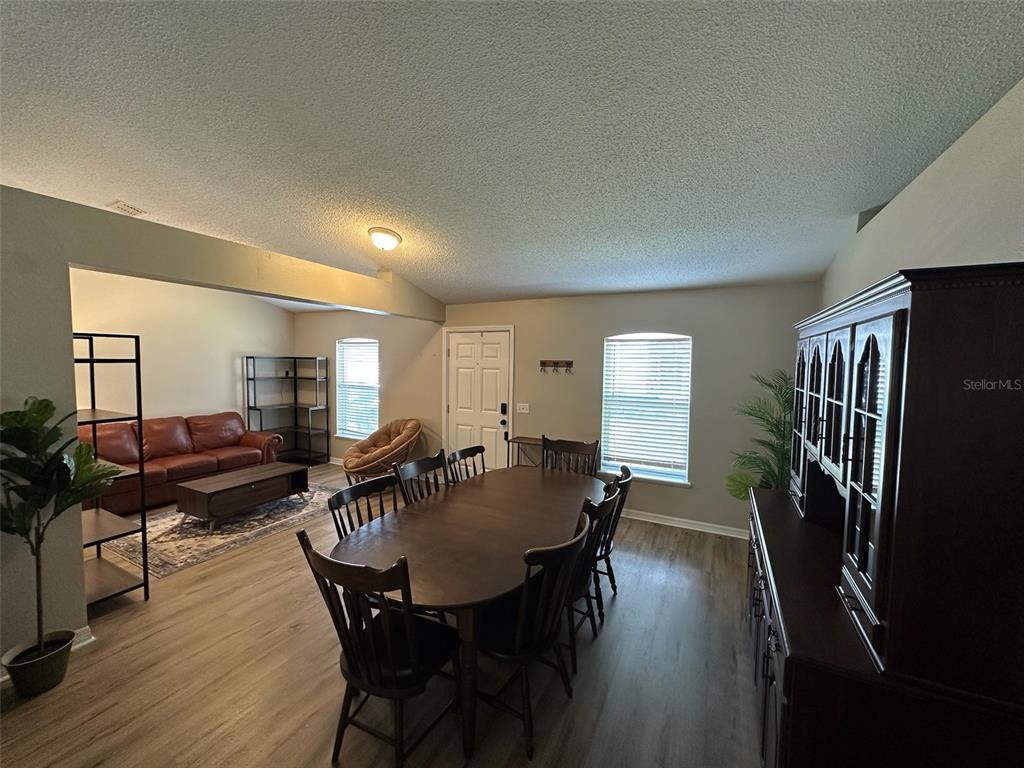 A dining area with a wooden table and chairs sits adjacent to a living room — 1346 DUNBARTON COURT, KISSIMMEE, FL