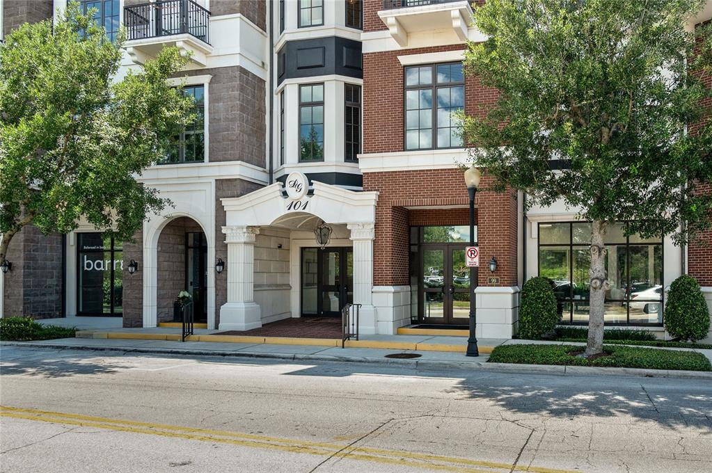 The exterior of a multi-story brick building features a prominent white arched entrance — 101 S NEW YORK AVENUE UNIT 311, WINTER PARK, FL