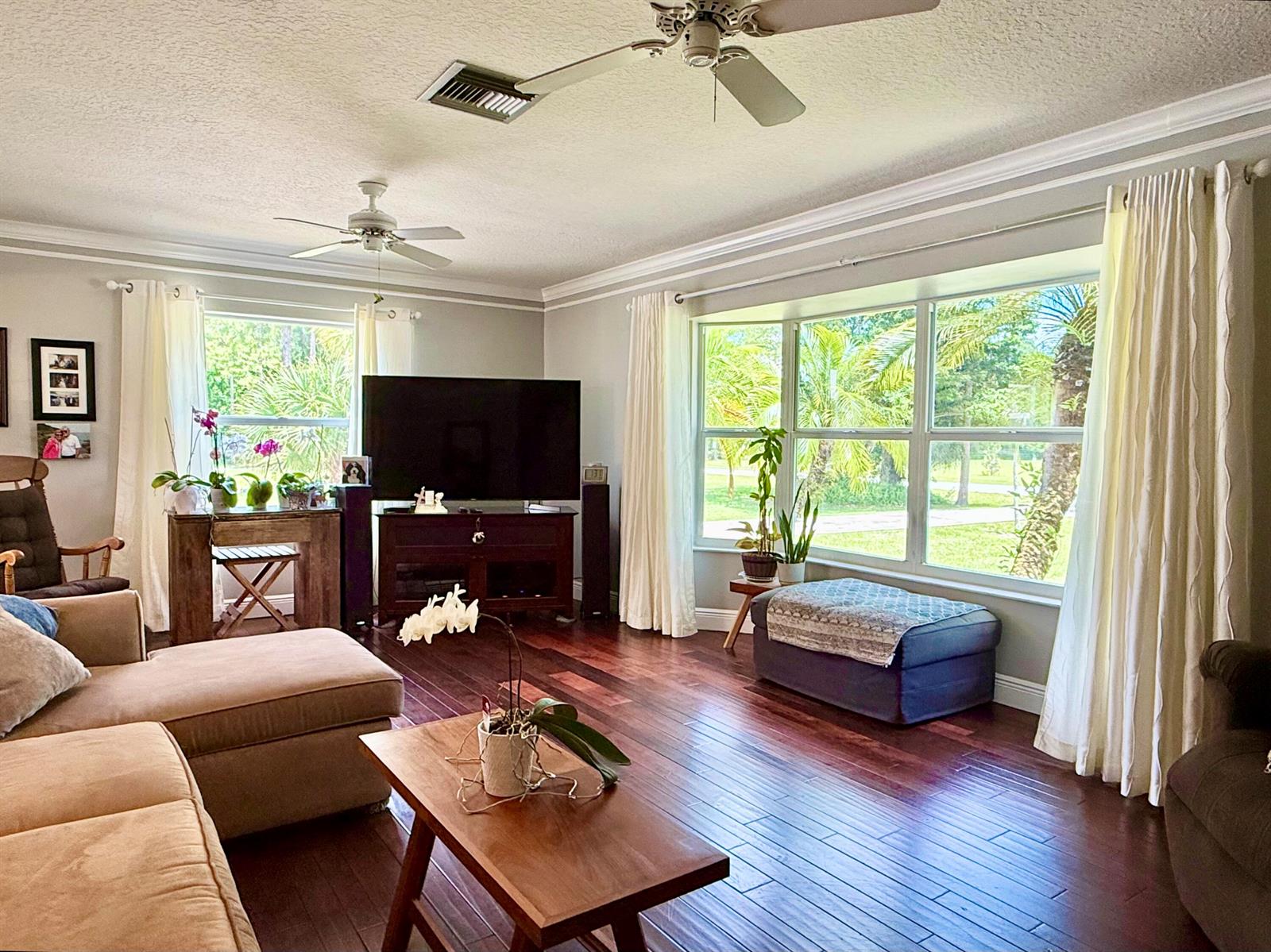 A living room features dark hardwood floors, a large sectional sofa, and a bay window — 16283 Alexander Run, Jupiter FL 33478, JUPITER, FL