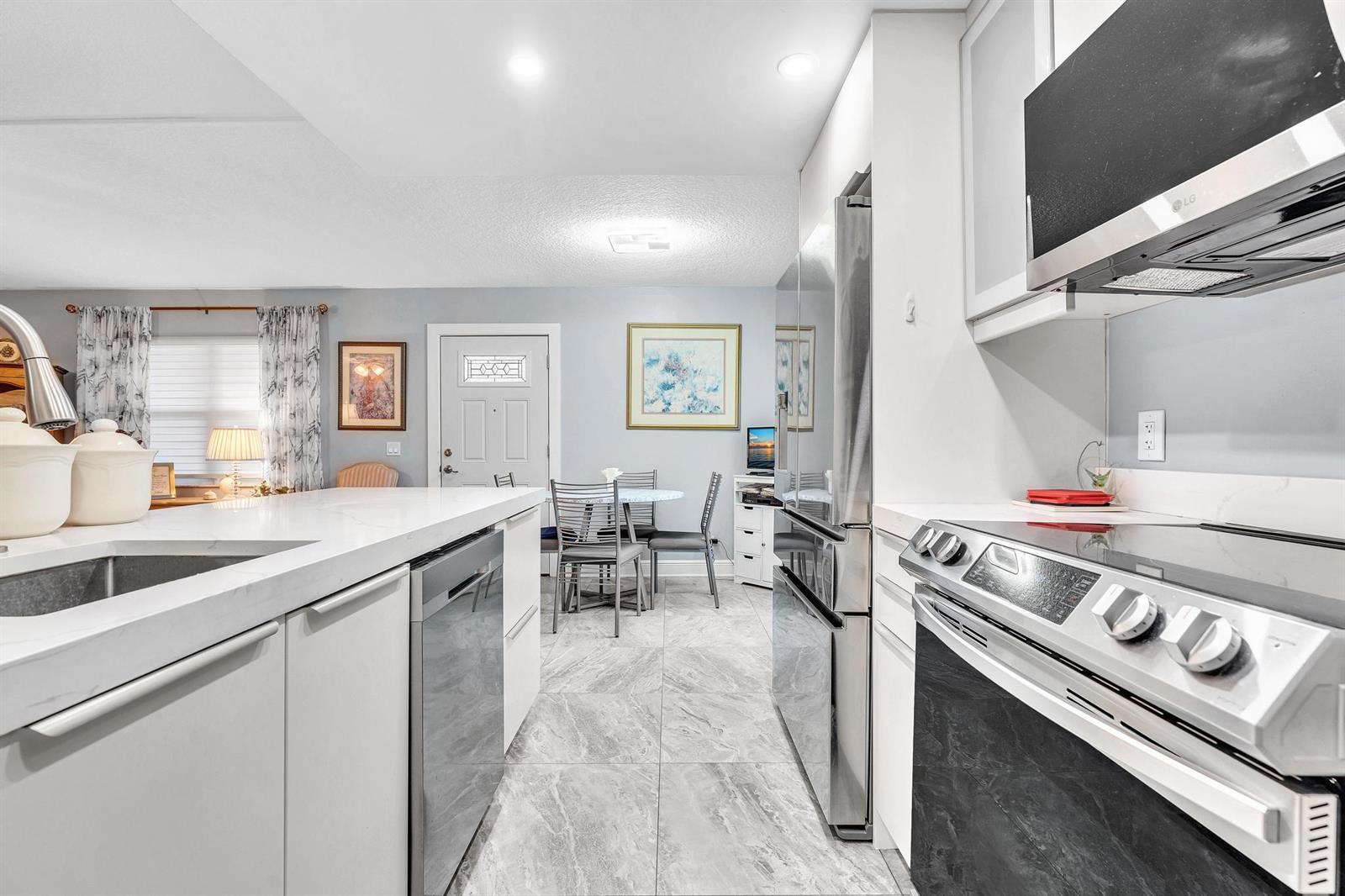A modern kitchen with white cabinets, stainless steel appliances, and a marble-patterned tile floor — 625 Normandy N # 625, Delray Beach FL 33484, DELRAY BEACH, FL