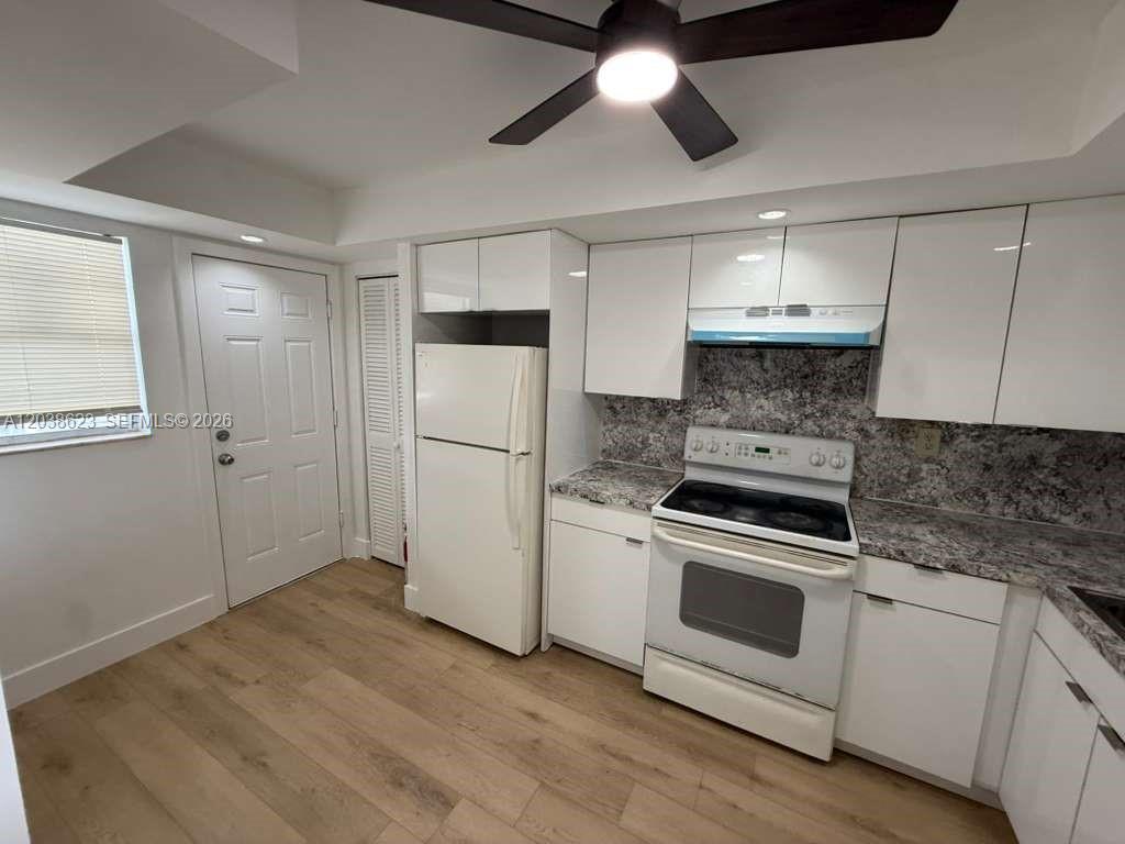 A kitchen features white cabinets, a white refrigerator, a white stove, and wood-look flooring — 1750 NE 191st St # 2, Miami FL 33179, MIAMI, FL