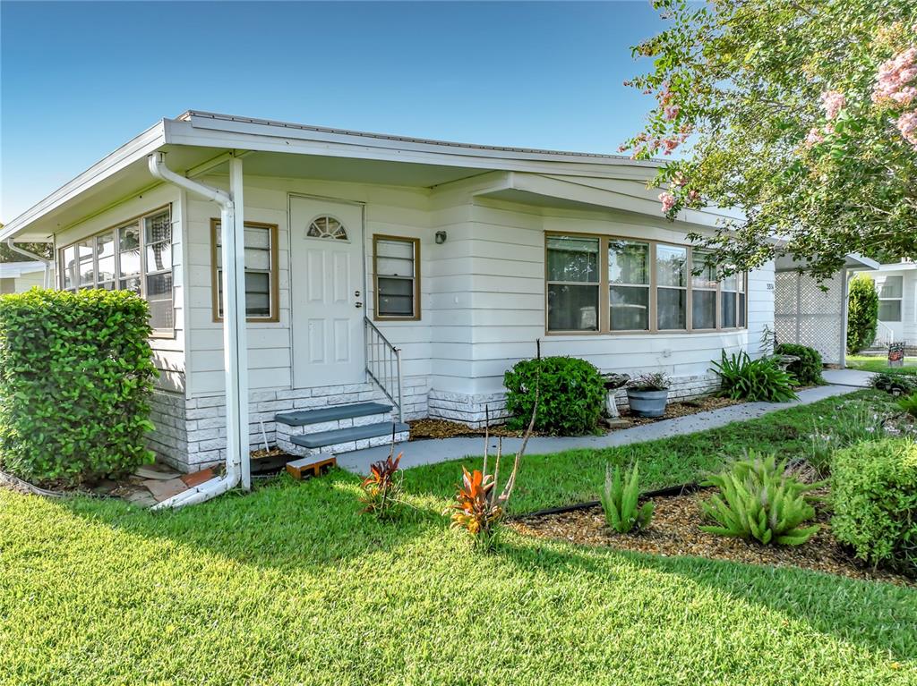 A white single-story manufactured home with a front door, stairs, and surrounding landscaping — 3374 EVERGREEN ROAD UNIT 1700, ZELLWOOD, FL
