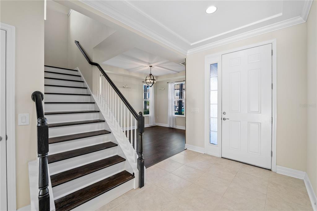 An entryway features a staircase with dark wood treads, white risers, and a white door — 4522 SCARLET LOOP, WESLEY CHAPEL, FL
