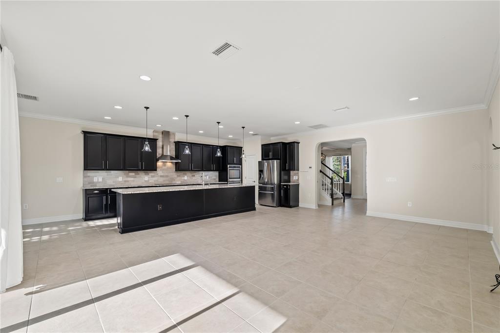 A spacious kitchen features black cabinetry, a large island, and light tile flooring — 4522 SCARLET LOOP, WESLEY CHAPEL, FL