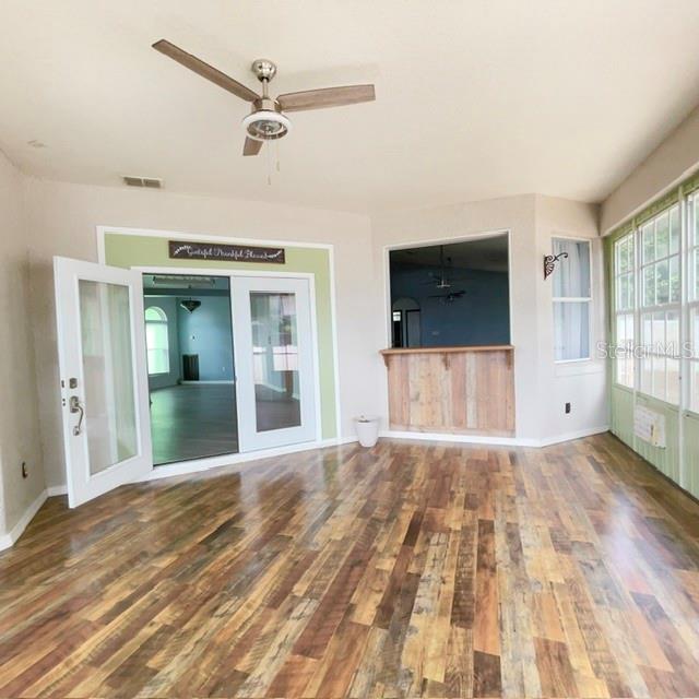 A sunroom with wood-look flooring, a ceiling fan, French doors, and a pass-through window — 259 NORWALK CIRCLE, EAGLE LAKE, FL
