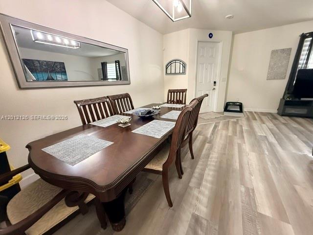 A dining room features a long wooden table, six chairs, and a large wall mirror — HIALEAH, FL