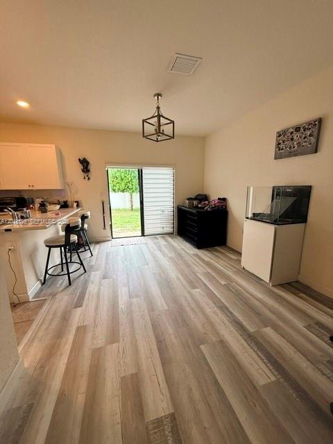 A kitchen with a breakfast bar, light wood flooring, and a sliding glass door — HIALEAH, FL