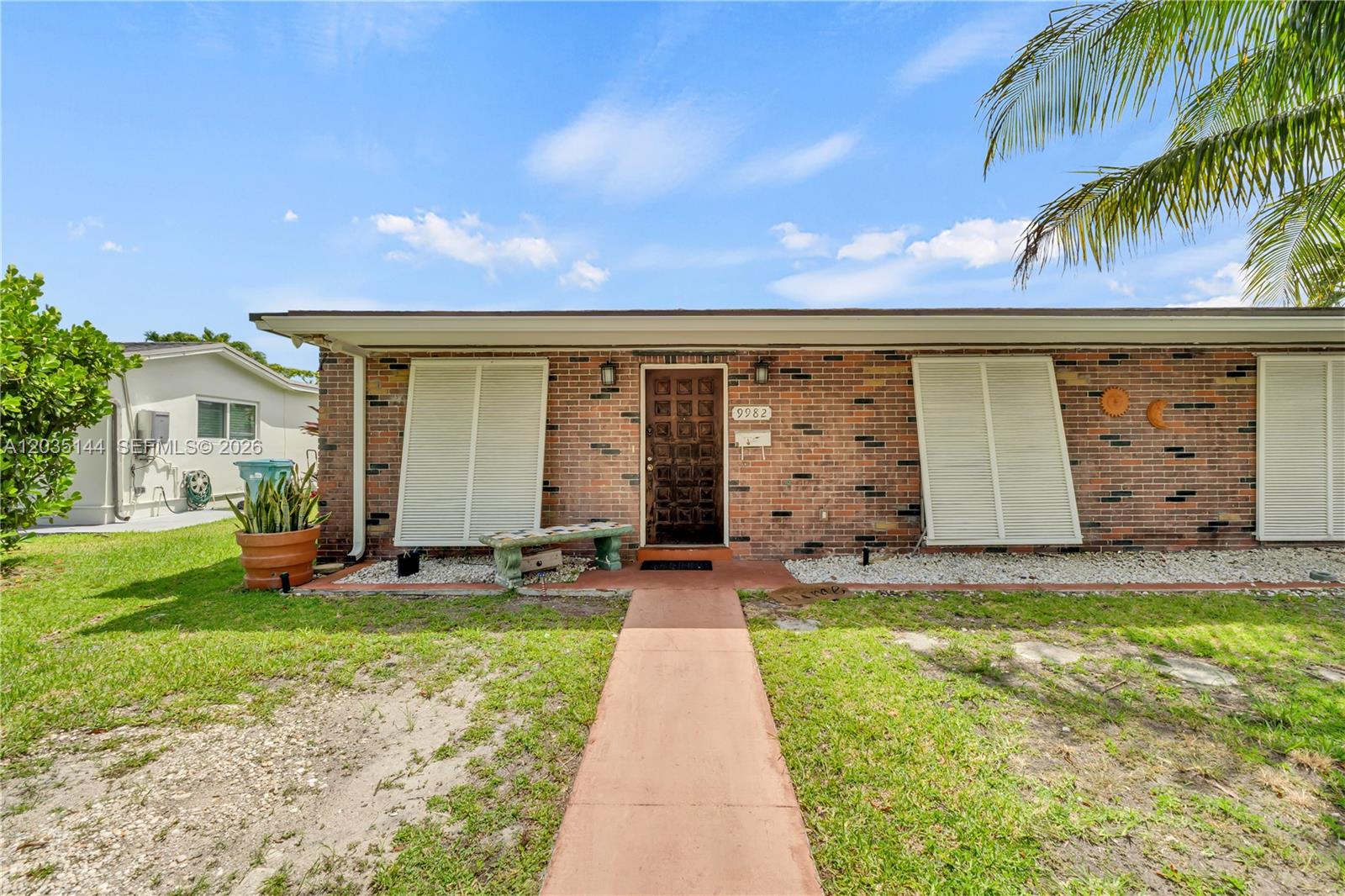 A single-story brick house features a brown front door, white shutters, and a concrete walkway — 9982 SW 196th St, Cutler Bay FL 33157, CUTLER BAY, FL