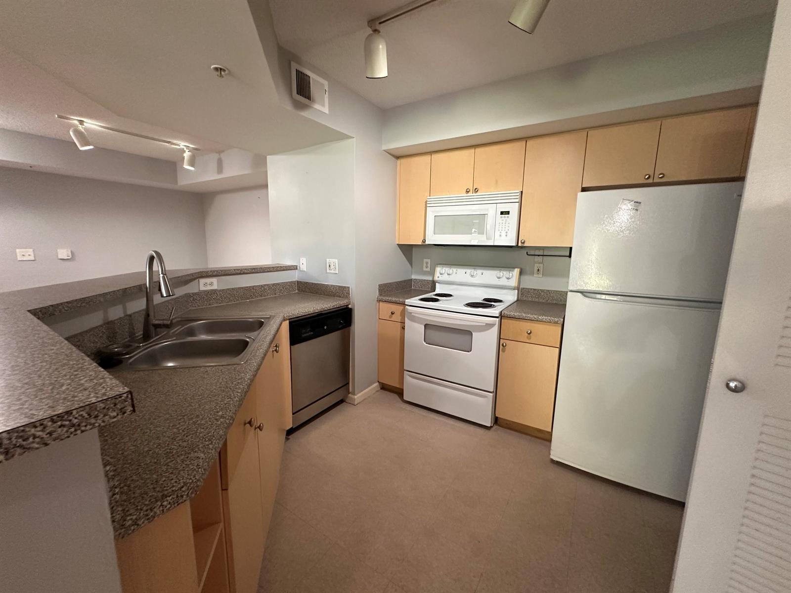 A kitchen features light wood cabinets, granite-look countertops, white appliances, and a stainless steel dishwasher — 3628 NW Adriatic Lane, Jensen Beach FL 34957, JENSEN BEACH, FL