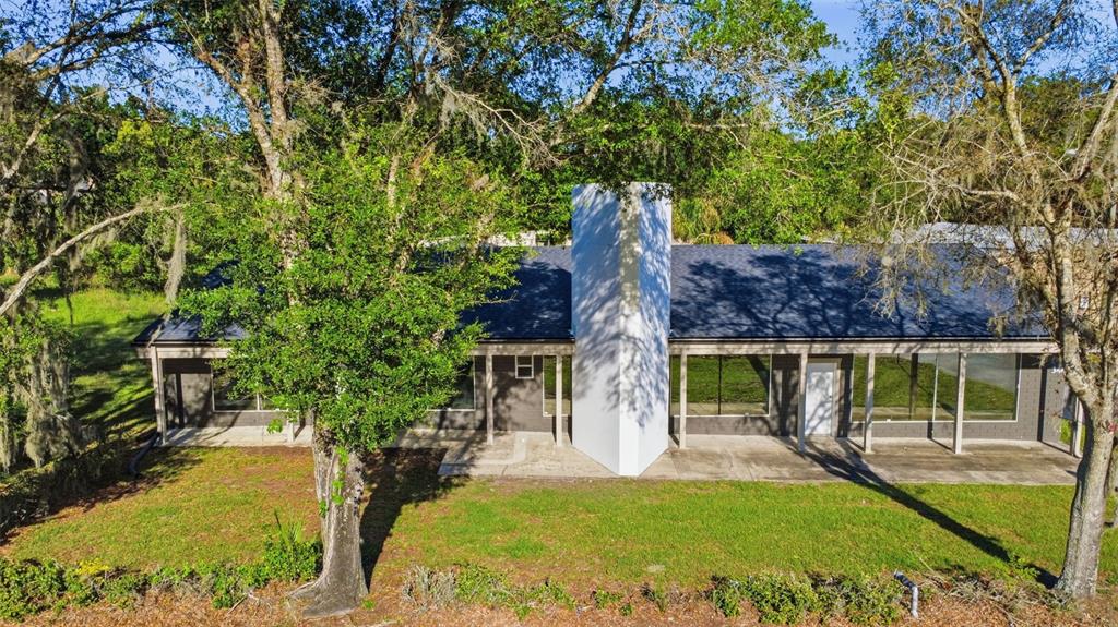 A rear exterior view of a single-story house with a large white central chimney — 346 N VOLUSIA AVENUE, ORANGE CITY, FL