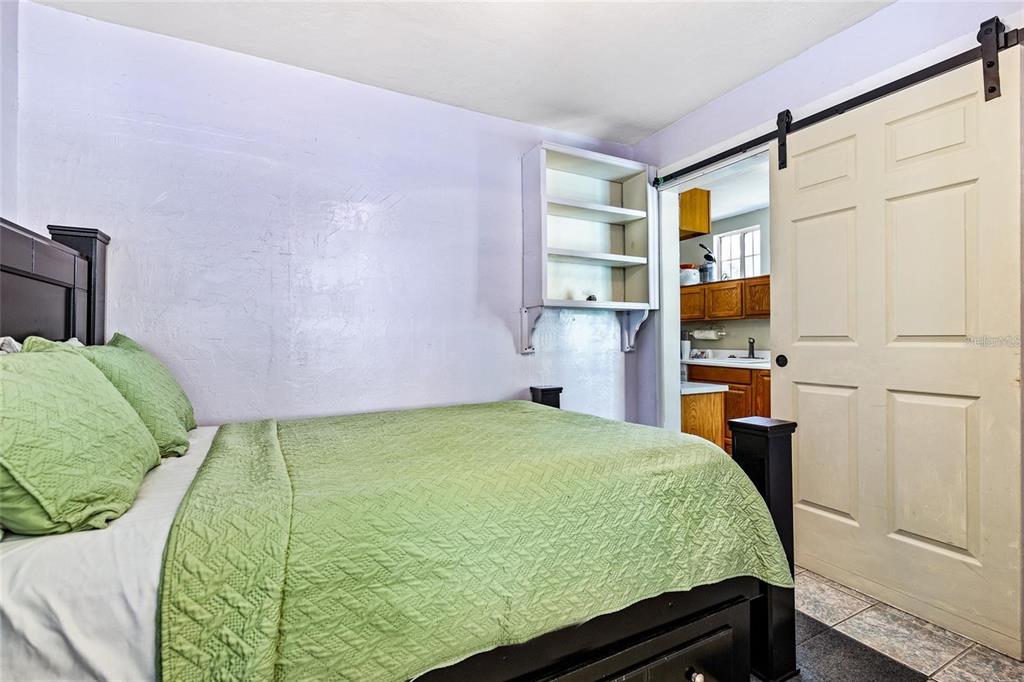 A bathroom with a white vanity, a glass shower stall, and a doorway leading into a kitchen — 1203 NW 12TH AVENUE, GAINESVILLE, FL