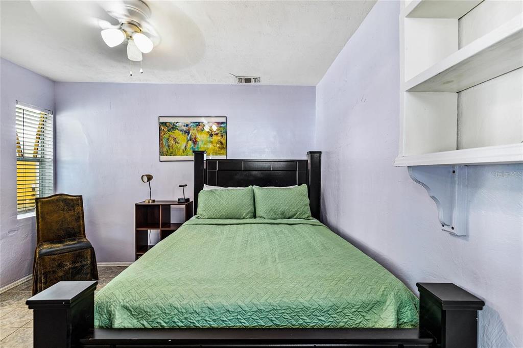 A bedroom features a bed with green bedding, a wall-mounted shelf, and a sliding barn door — 1203 NW 12TH AVENUE, GAINESVILLE, FL