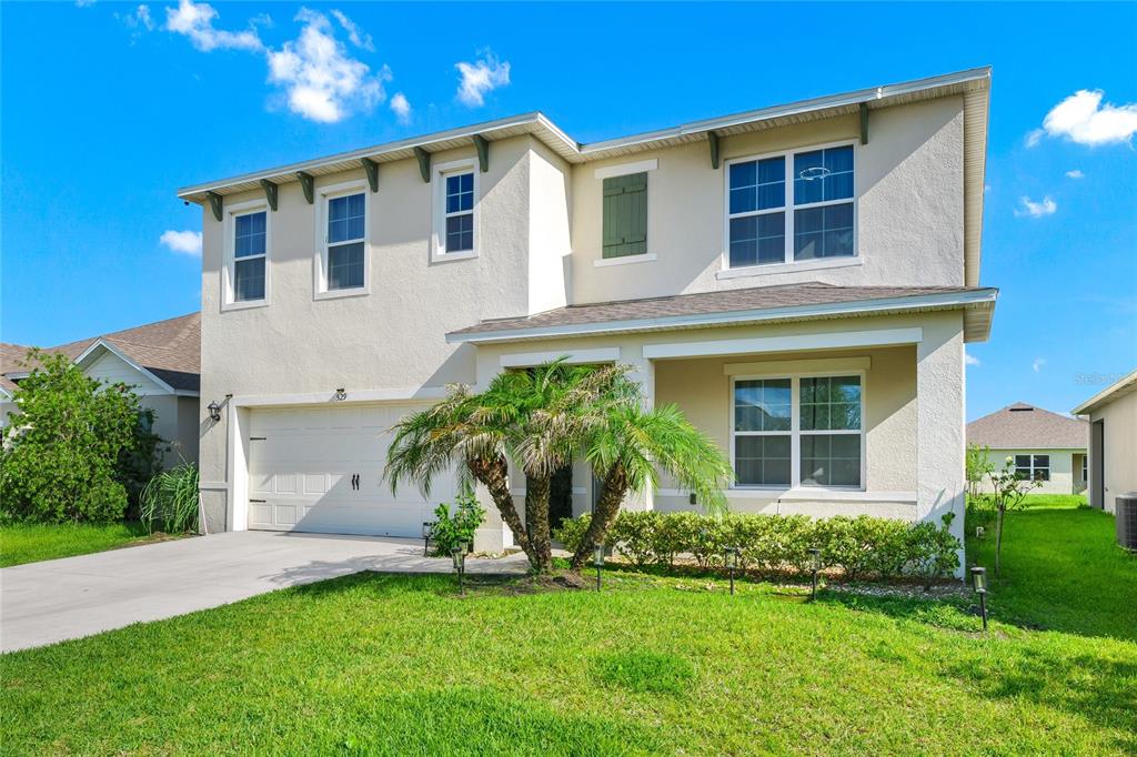 A two-story suburban house with a beige stucco exterior, a two-car garage, and a palm tree — 529 TALISI LOOP, ST CLOUD, FL