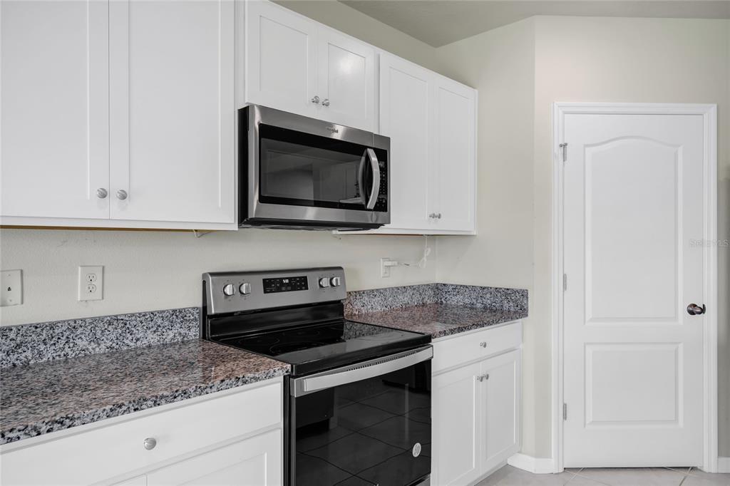 A kitchen features white cabinets, granite countertops, a stainless steel microwave, and a black stove — 529 TALISI LOOP, ST CLOUD, FL