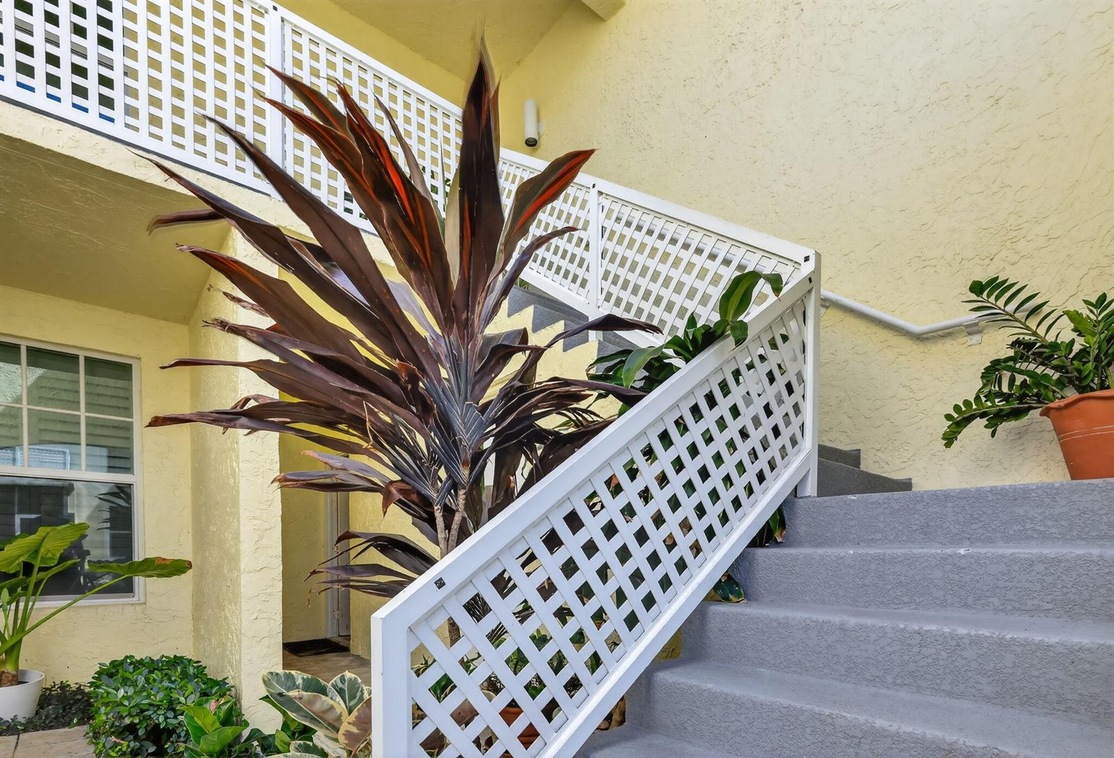 A set of gray outdoor stairs with white lattice railings leads up to a building exterior — 1403 Mainsail Circle, Jupiter FL 33477, JUPITER, FL