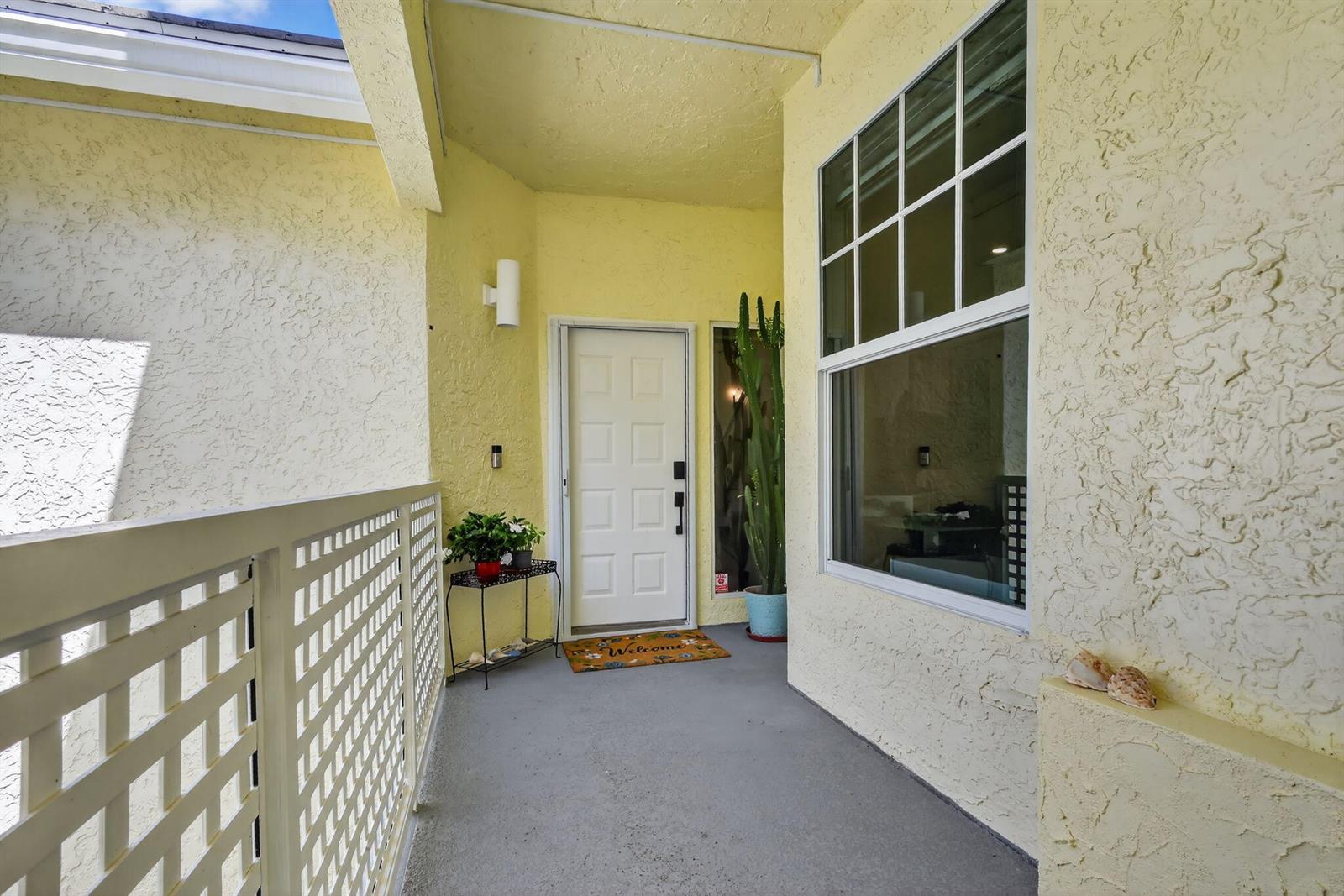 A covered entryway features a white door, a large cactus, and a lattice railing — 1403 Mainsail Circle, Jupiter FL 33477, JUPITER, FL