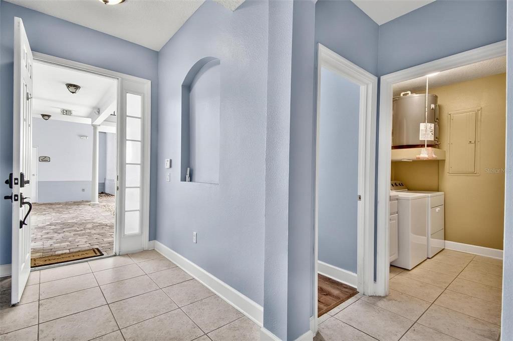An entryway with light blue walls, tile flooring, an arched niche, and a laundry closet — 200 RIVERFRONT DRIVE UNIT D103, PALM COAST, FL