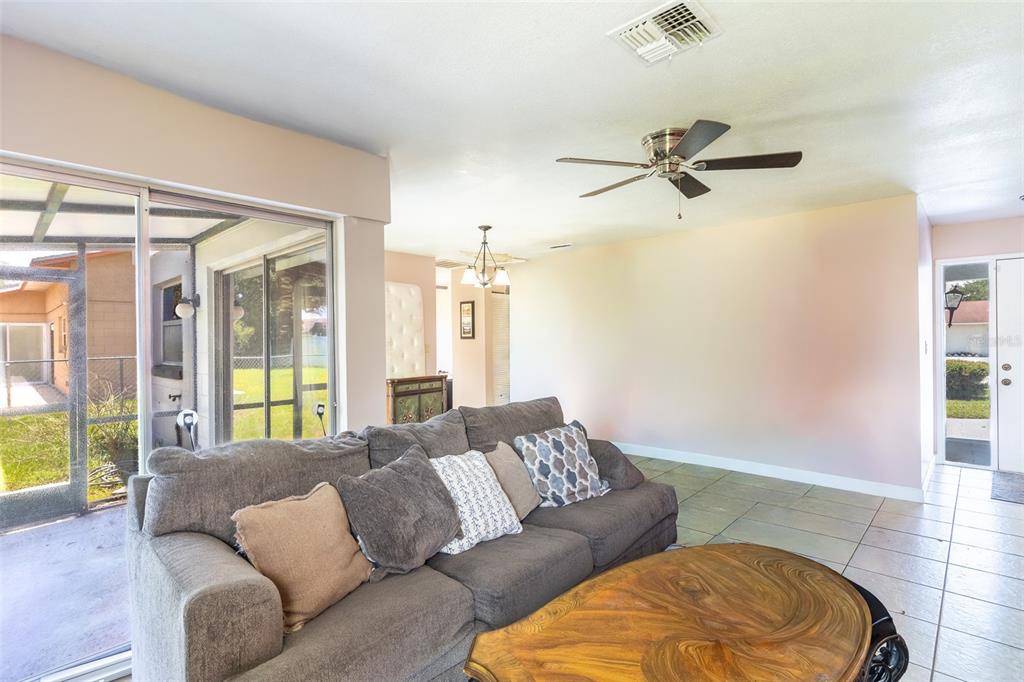 A living room features a gray sofa, a wooden coffee table, and sliding glass doors — 443 BALL COURT, KISSIMMEE, FL