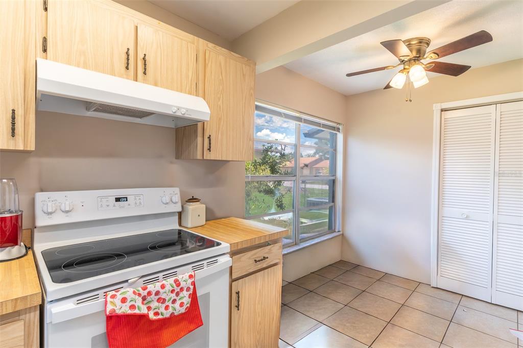 A kitchen features light wood cabinets, a white electric stove, and tile flooring — 443 BALL COURT, KISSIMMEE, FL