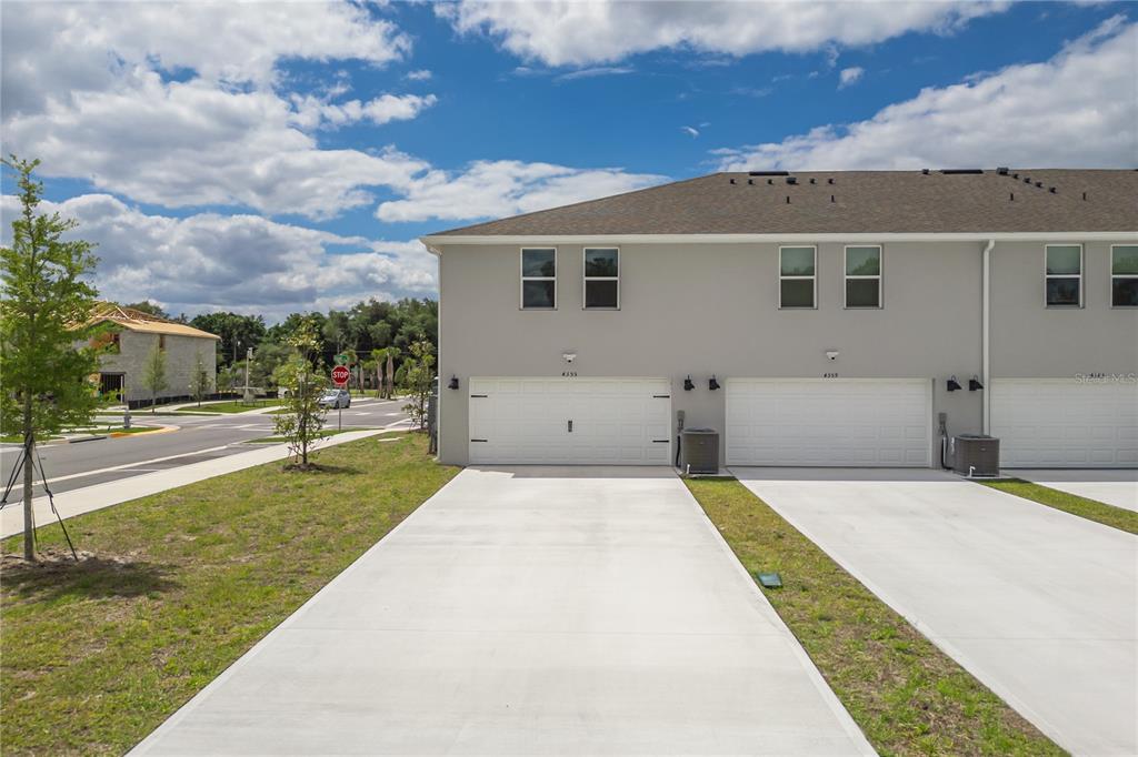 A view of the exterior of a modern townhome with a concrete driveway and garage — 4355 HAZEL STREET, KISSIMMEE, FL