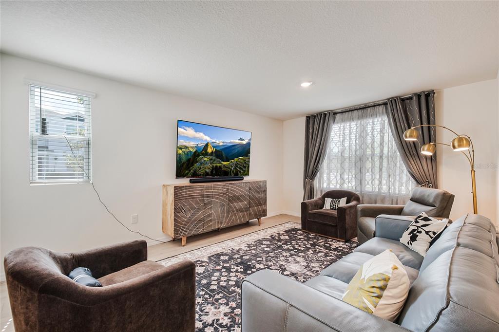 A living room features a television on a patterned console, a sofa, and two armchairs — 4355 HAZEL STREET, KISSIMMEE, FL