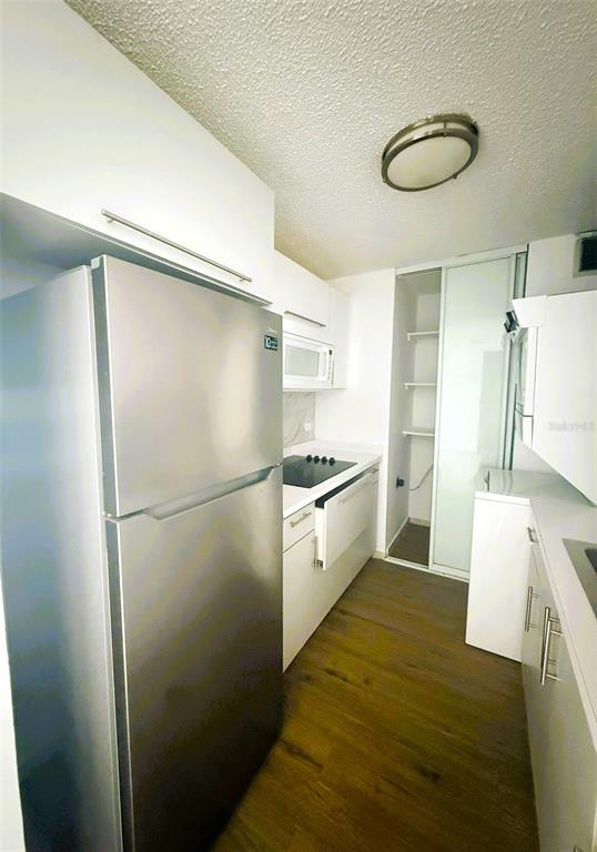 A narrow kitchen features stainless steel appliances, white cabinetry, and wood-look flooring — 3 CALLE HORTENSIA UNIT 17E, SAN JUAN, PR