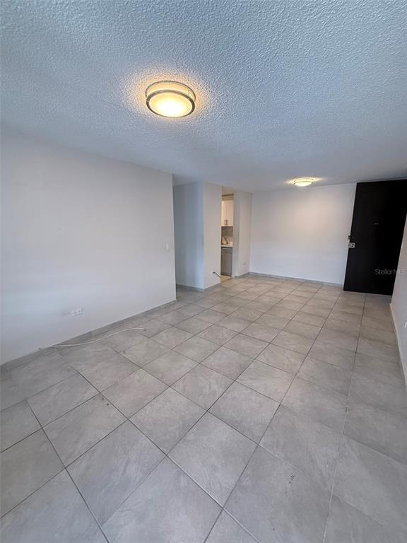 An empty room with gray tile flooring, white walls, and two ceiling-mounted light fixtures — 3 CALLE HORTENSIA UNIT 17E, SAN JUAN, PR