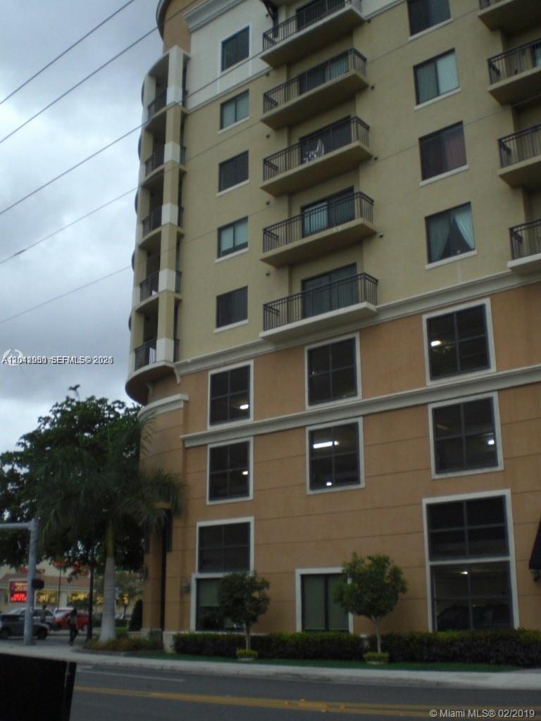 A low-angle exterior view of a multi-story tan apartment building with balconies — 3590 CORAL WAY # 902, Miami FL 33145, MIAMI, FL