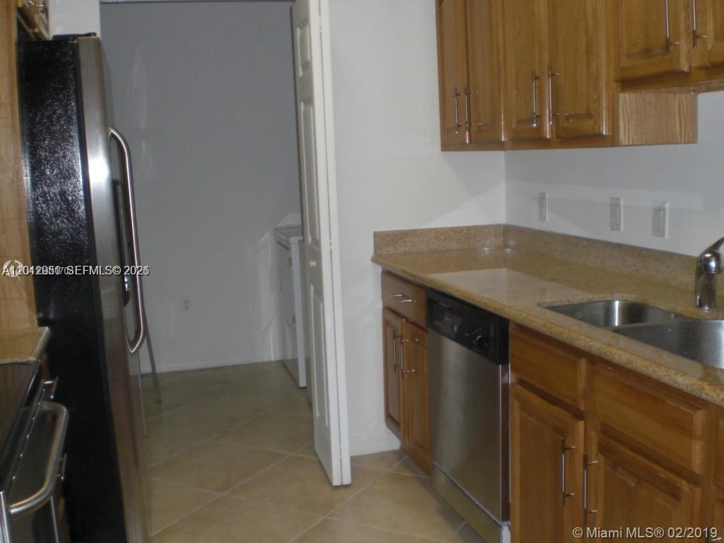 A kitchen features wood cabinets, granite countertops, a stainless steel dishwasher, and a black refrigerator — 3590 CORAL WAY # 902, Miami FL 33145, MIAMI, FL
