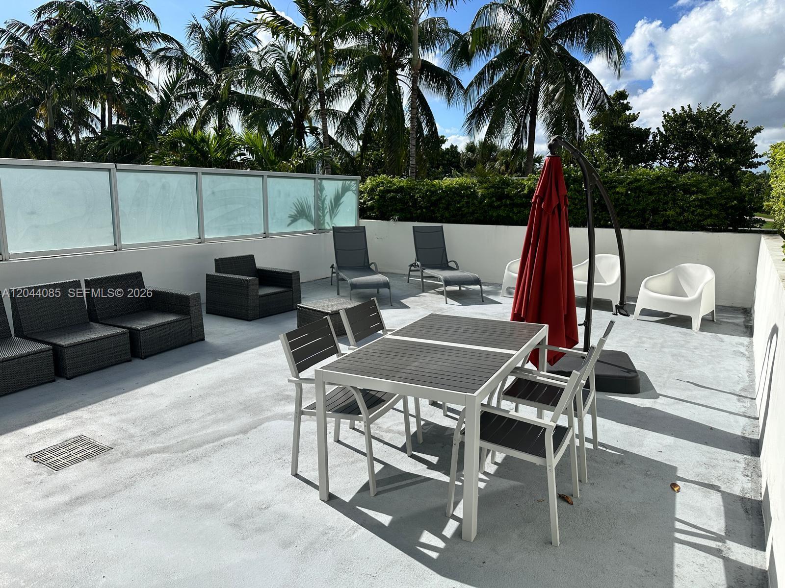 An outdoor rooftop terrace features a dining set, lounge chairs, and a red patio umbrella — 2001 Meridian Ave # 309, Miami Beach FL 33139, MIAMI BEACH, FL