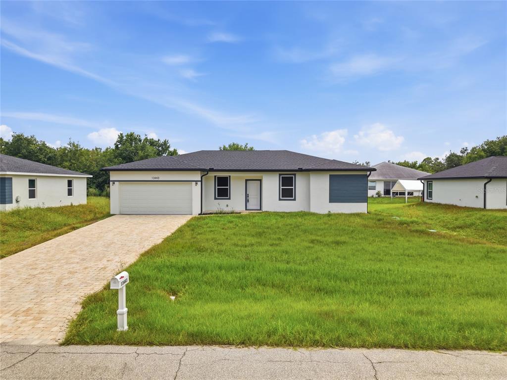 A single-story house with a white exterior, dark roof, and a paved driveway — 13443 KAPLAN TERRACE, PORT CHARLOTTE, FL