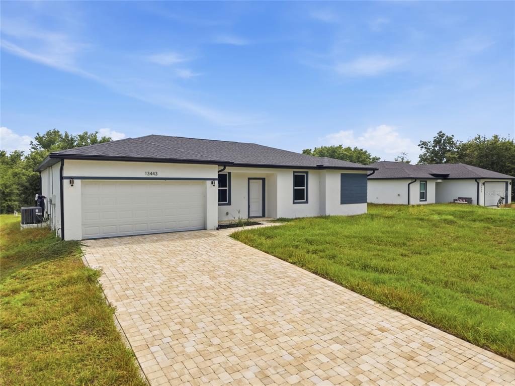 A single-story house with a white stucco exterior, a paved driveway, and a two-car garage — 13443 KAPLAN TERRACE, PORT CHARLOTTE, FL
