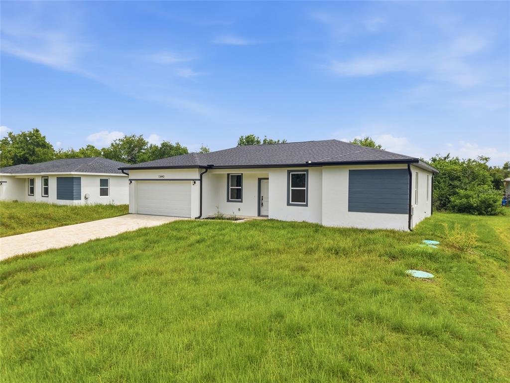 A white single-story house with a gray roof, garage, and a large grassy yard — 13443 KAPLAN TERRACE, PORT CHARLOTTE, FL