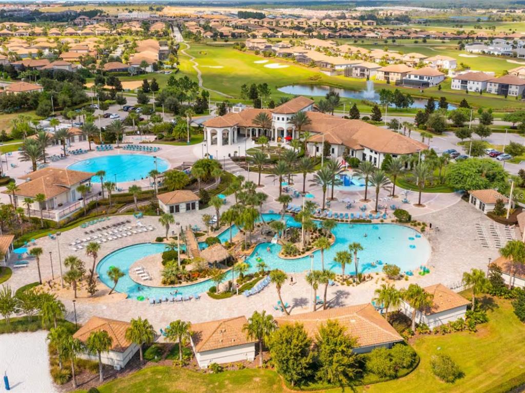 An aerial view of a community clubhouse featuring two swimming pools and surrounding residential homes — 1043 SPLASH SHOT PLACE UNIT 2002, DAVENPORT, FL
